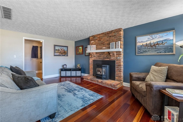 living room featuring visible vents, a textured ceiling, baseboards, and wood finished floors