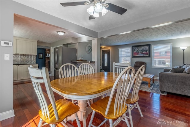 dining space featuring baseboards, a textured ceiling, dark wood finished floors, and a ceiling fan