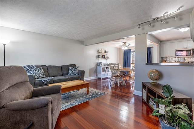 living area featuring hardwood / wood-style floors, a ceiling fan, baseboards, and a textured ceiling