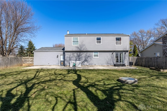 back of house with a fenced backyard, a lawn, and a patio