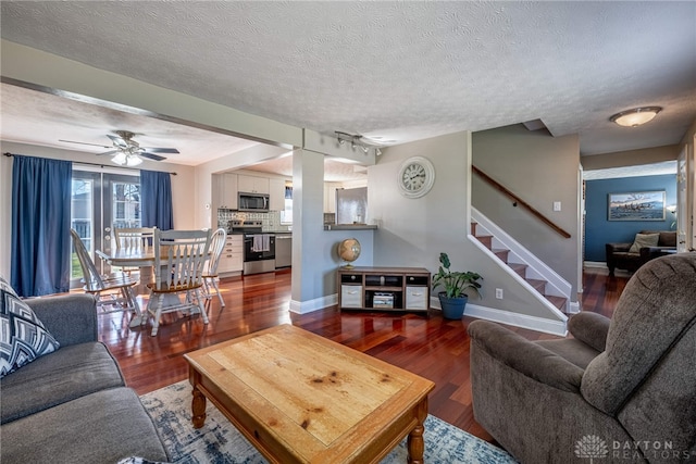 living room with stairway, wood finished floors, baseboards, and a textured ceiling