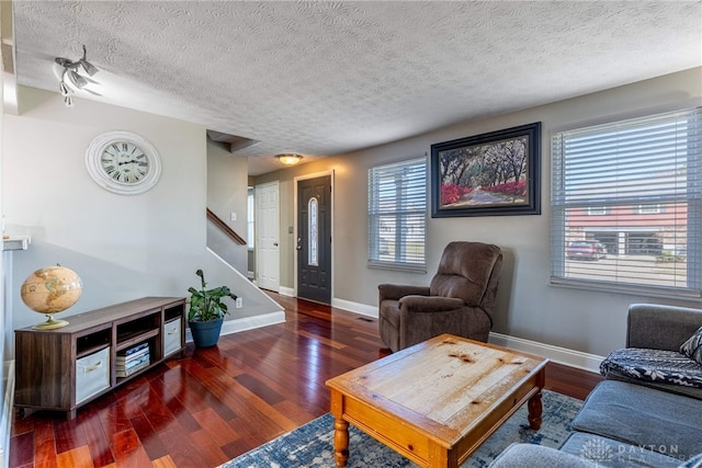 living room featuring stairway, wood finished floors, baseboards, and a textured ceiling