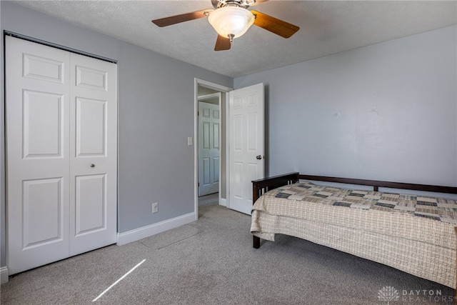 carpeted bedroom with a ceiling fan, baseboards, a closet, and a textured ceiling