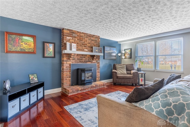 living room with baseboards, a textured ceiling, wood finished floors, and a wood stove