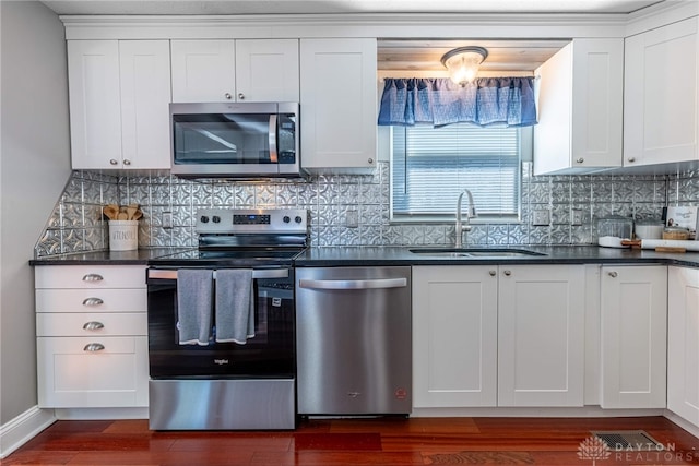 kitchen featuring dark wood finished floors, dark countertops, appliances with stainless steel finishes, and a sink