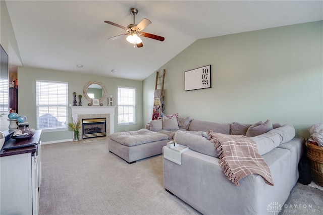 living room with light carpet, a tiled fireplace, baseboards, ceiling fan, and vaulted ceiling