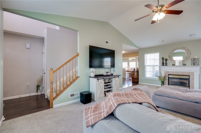 carpeted living area with baseboards, ceiling fan, stairway, lofted ceiling, and a fireplace