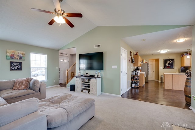 carpeted living room featuring visible vents, baseboards, ceiling fan, stairs, and vaulted ceiling