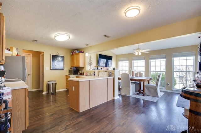 kitchen featuring visible vents, a peninsula, freestanding refrigerator, ceiling fan, and light countertops