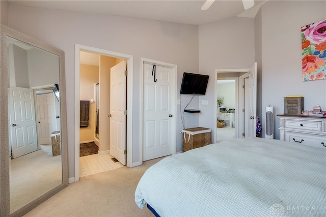 bedroom with a ceiling fan, baseboards, high vaulted ceiling, ensuite bathroom, and light carpet