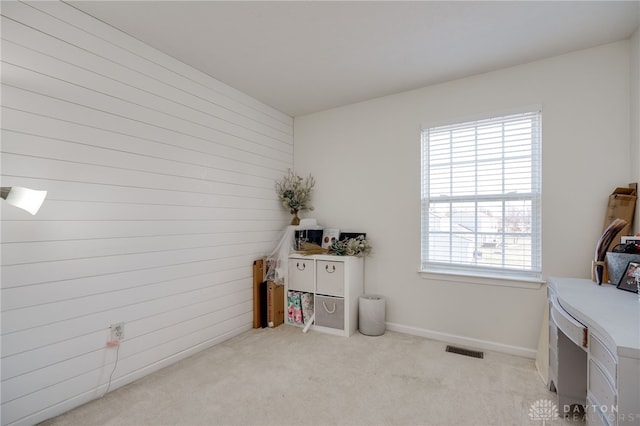 interior space with wooden walls, carpet flooring, baseboards, and visible vents