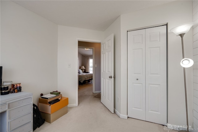 bedroom with baseboards, a closet, and light carpet