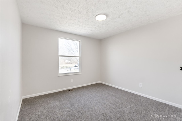 spare room with visible vents, carpet flooring, a textured ceiling, and baseboards