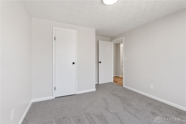 unfurnished bedroom with baseboards, a textured ceiling, and carpet flooring