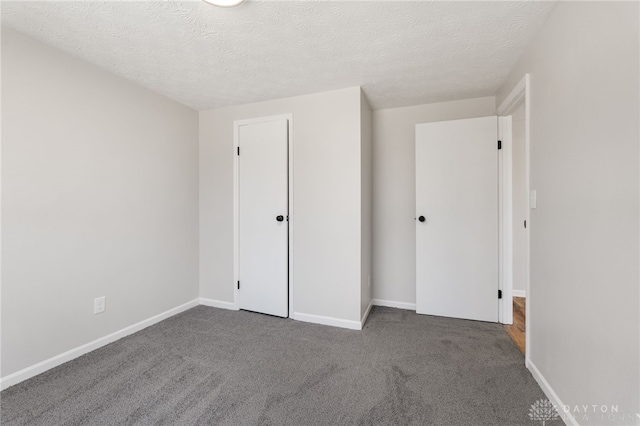 unfurnished bedroom with carpet, baseboards, and a textured ceiling