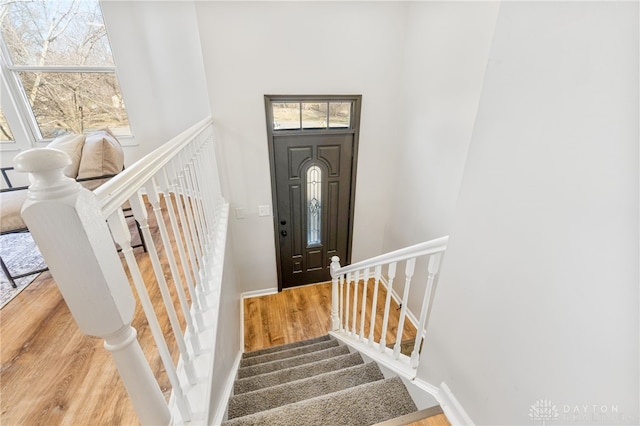 entrance foyer with stairs, a high ceiling, baseboards, and wood finished floors