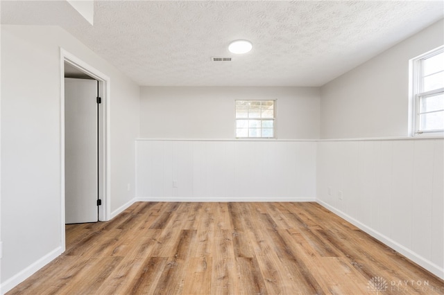 unfurnished room with plenty of natural light, wood finished floors, and wainscoting