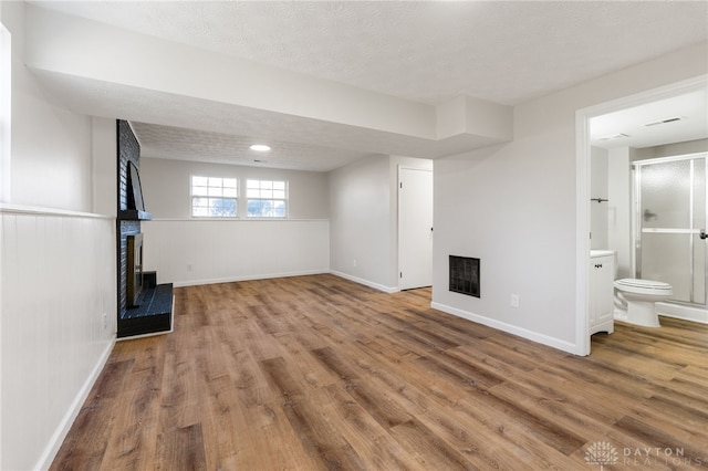 below grade area featuring wood finished floors, a fireplace, baseboards, and a textured ceiling