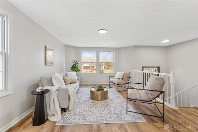 living room featuring a textured ceiling, baseboards, and wood finished floors