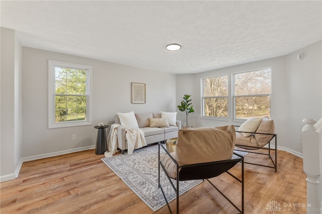 living area with baseboards, light wood finished floors, and a textured ceiling