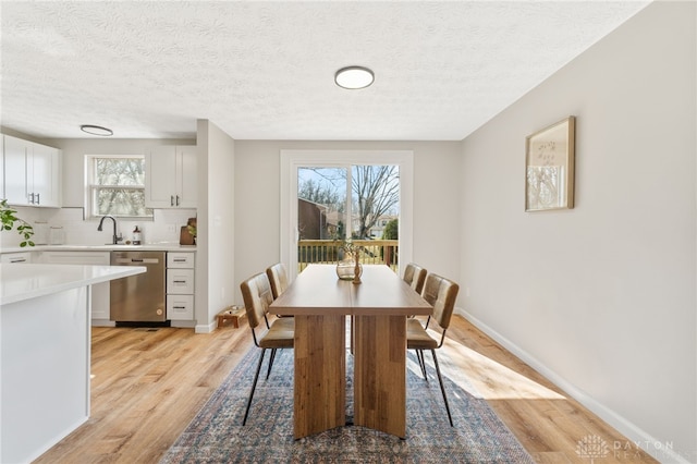 dining room featuring baseboards, light wood-type flooring, and a textured ceiling