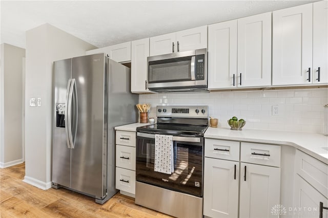 kitchen featuring stainless steel appliances, backsplash, light wood-style flooring, and light countertops