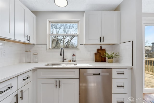 kitchen with a sink, a textured ceiling, white cabinets, decorative backsplash, and dishwasher