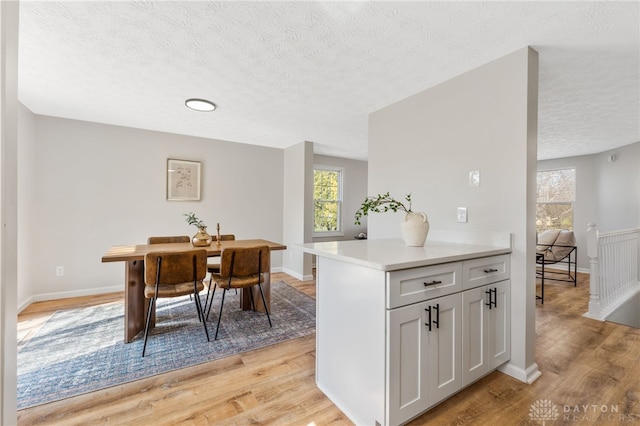 dining room featuring baseboards, light wood finished floors, and a textured ceiling