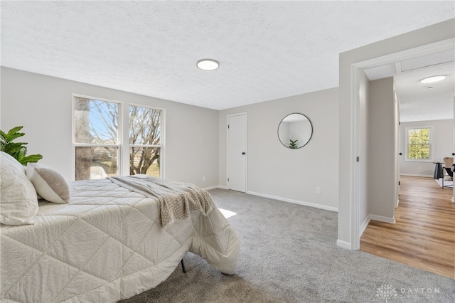 bedroom with carpet, baseboards, and a textured ceiling