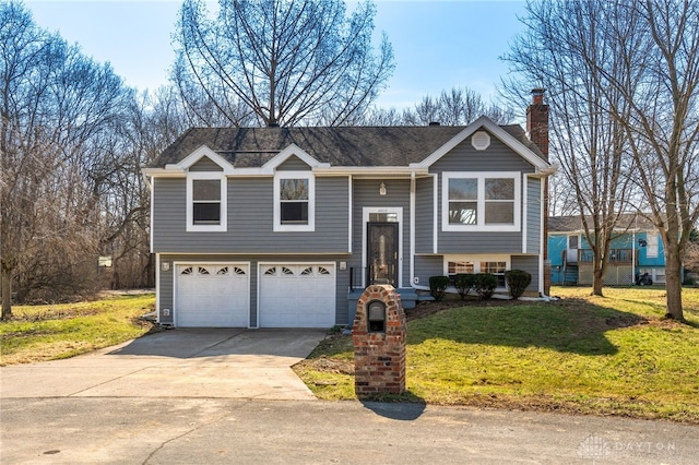 bi-level home with concrete driveway, an attached garage, a front yard, and a chimney