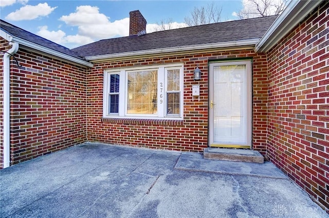 entrance to property featuring brick siding and a chimney