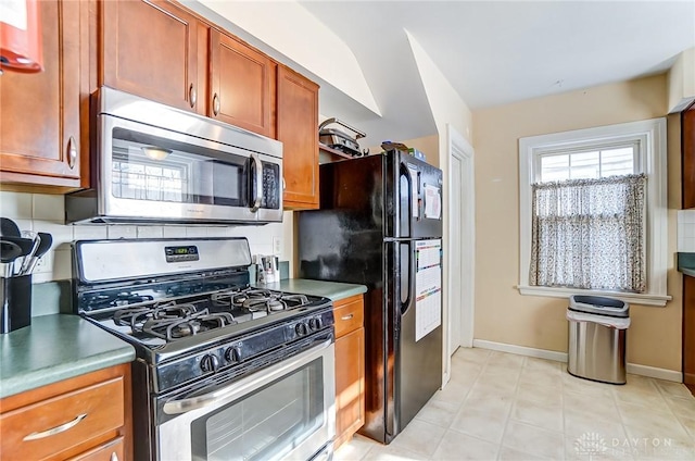 kitchen with backsplash, appliances with stainless steel finishes, and baseboards