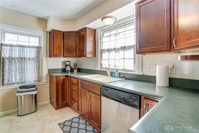 kitchen with baseboards, light tile patterned flooring, a sink, stainless steel dishwasher, and tasteful backsplash