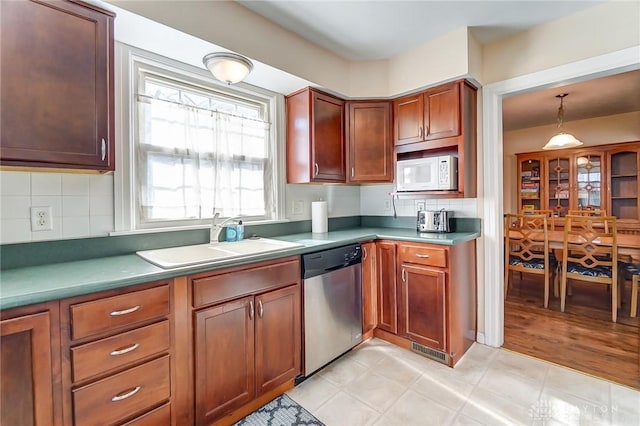 kitchen with visible vents, a sink, tasteful backsplash, white microwave, and dishwasher