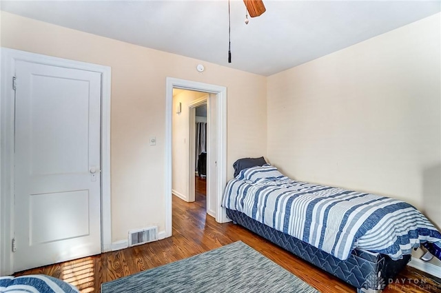 bedroom with ceiling fan, visible vents, baseboards, and wood finished floors