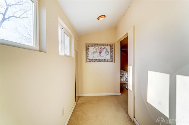 corridor with light carpet, baseboards, and lofted ceiling