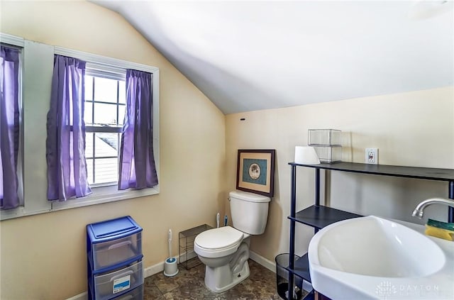 half bathroom featuring vaulted ceiling, toilet, baseboards, and a sink