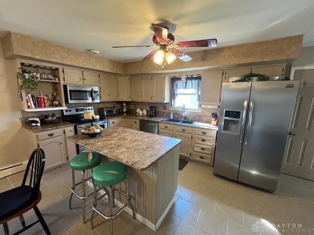 kitchen with a kitchen bar, a ceiling fan, a sink, a kitchen island, and stainless steel appliances