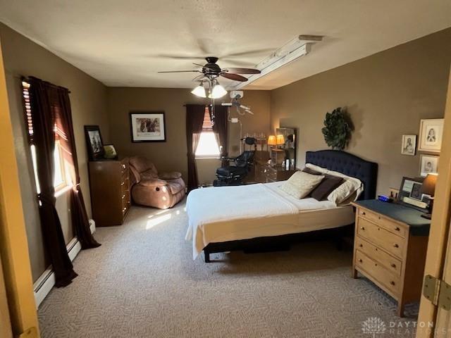 bedroom featuring a baseboard heating unit, light colored carpet, baseboard heating, and ceiling fan