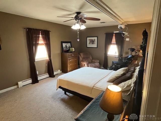 bedroom featuring baseboards, multiple windows, baseboard heating, and carpet floors