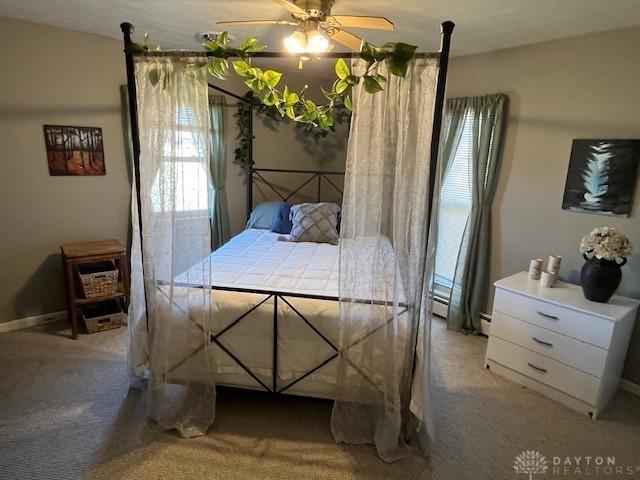 bedroom with light carpet, multiple windows, and a baseboard radiator