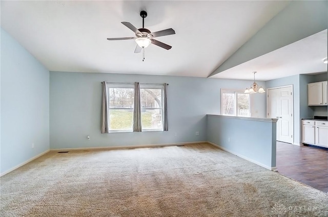 unfurnished living room with vaulted ceiling, carpet flooring, ceiling fan with notable chandelier, and baseboards