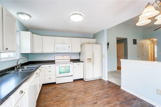 kitchen featuring dark countertops, white cabinets, white appliances, and a sink