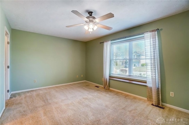 empty room featuring carpet, visible vents, a ceiling fan, and baseboards