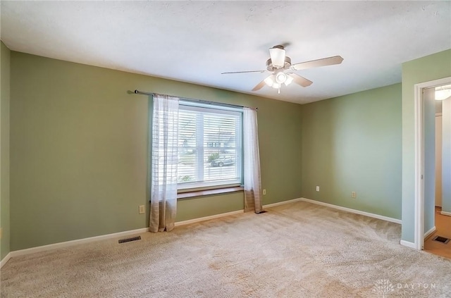 empty room with visible vents, baseboards, carpet flooring, and a ceiling fan