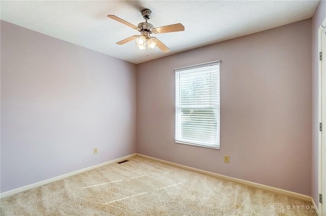 spare room with visible vents, carpet floors, baseboards, and ceiling fan