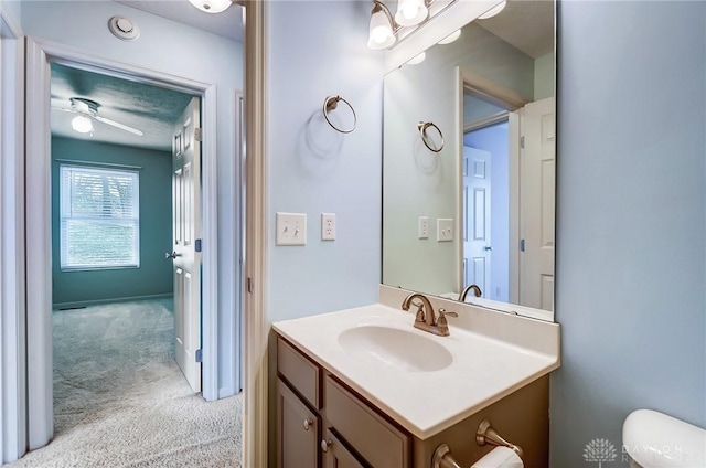 half bathroom featuring toilet, ceiling fan, and vanity