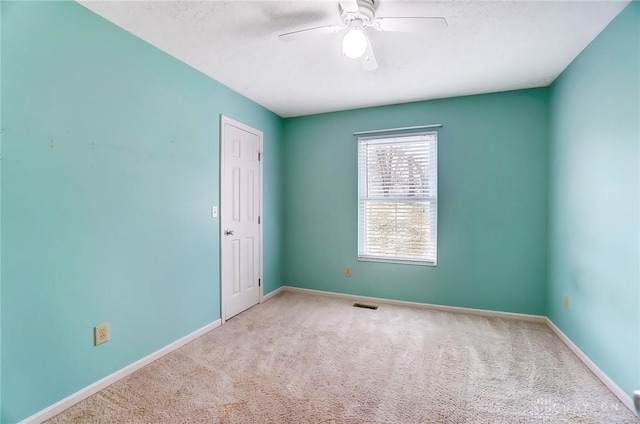 carpeted empty room with visible vents, baseboards, and a ceiling fan