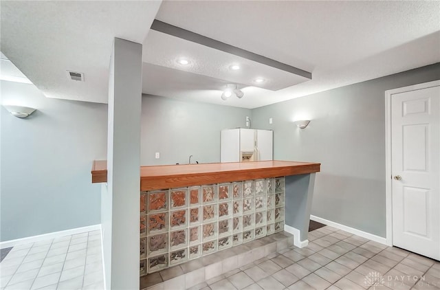 bar with visible vents, baseboards, a sink, indoor wet bar, and white refrigerator with ice dispenser