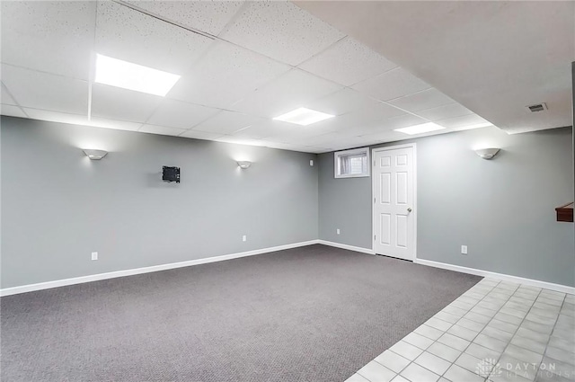 below grade area with a drop ceiling, baseboards, visible vents, and carpet floors